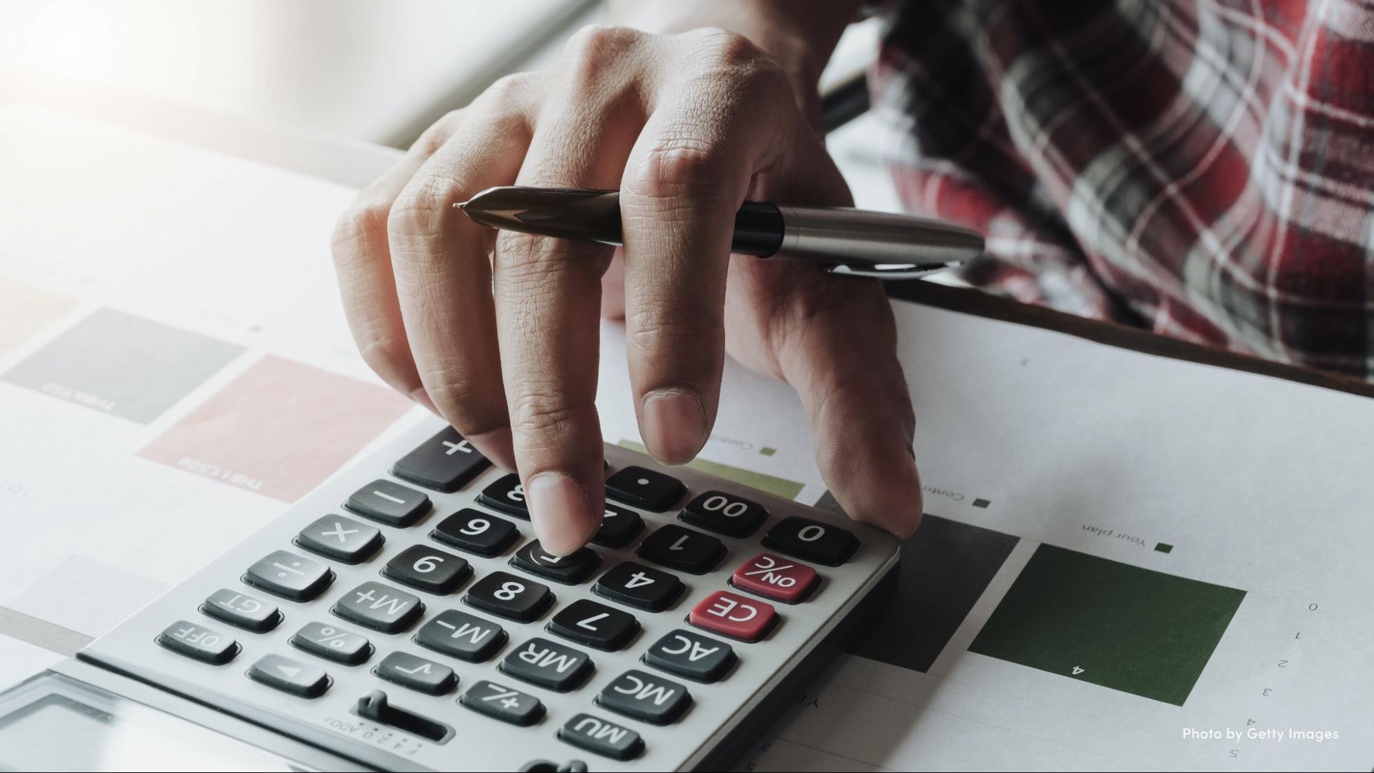 Close-up photo of a man using a calculator.